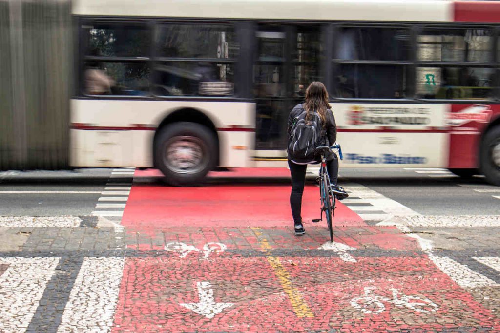 mulher ciclista em sao paulo na ciclovia espera passagem de onibus em avenida