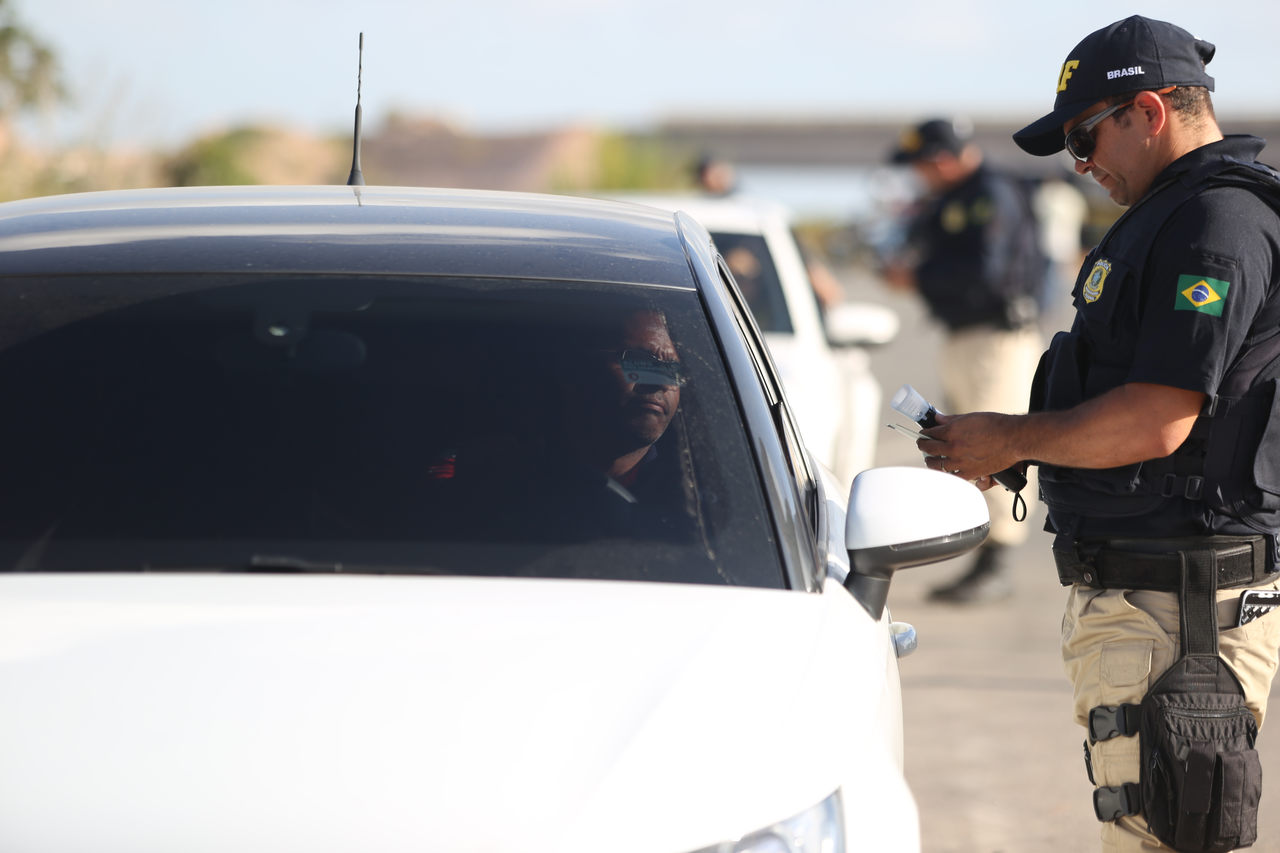 policial rodoviario federal para motorista de carro branco em rodovia