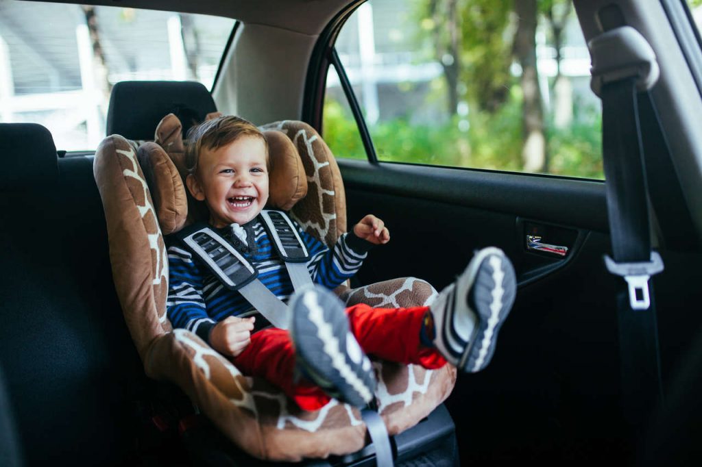 criança em assento infantil de carro dá risada